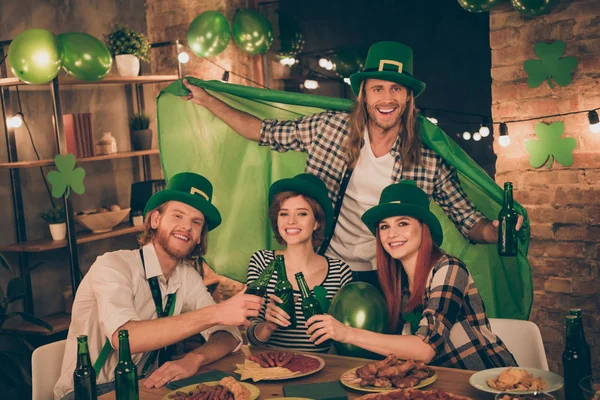 Close up photo celebrating company together st paddy day mood green leprechaun hats balloons flag table full of food eat tell speak talk toasts meet new guests decorated flat apartments