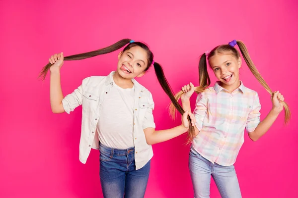 Close-up foto duas meninas muito pequena idade feriado se divertindo infantil feliz língua para fora piscando boca jogando vestindo jeans casuais jeans xadrez camisas isoladas rosa viva vibrante fundo — Fotografia de Stock