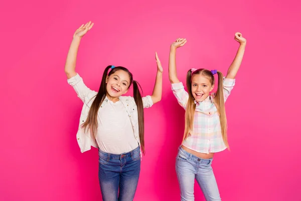 De cerca la foto dos niñas bastante pequeña edad vacaciones divertido baile alegre manos hasta niños fiesta disco con vaqueros vaqueros casuales camisas a cuadros aislados rosa vívido fondo vibrante —  Fotos de Stock
