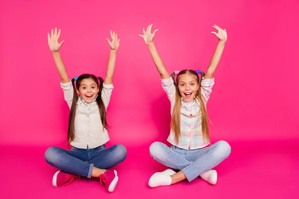 Närbild foto två lite ålder hon hennes flickor händer armar upp bästa vänner sit golvet ben korsade vinnare bär casual jeans denim rutig pläd skjortor isolerade ros pulserande levande bakgrund — Stockfoto