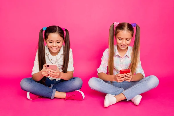 Close up foto duas pessoas pouca idade ela suas meninas segurar as mãos braços telefones bate-papo pais sentar-se chão desgaste casual jeans jeans xadrez camisas isoladas rosa vibrante fundo vívido — Fotografia de Stock