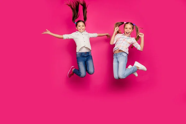 Ganzkörpergröße Foto zwei wenig Alter sie ihre Mädchen springen hoch gewinnen Schulwettbewerb Cheerleader tragen lässige Jeans Jeans karierten karierten Hemden isoliert rosa Rose lebendigen lebendigen Hintergrund — Stockfoto
