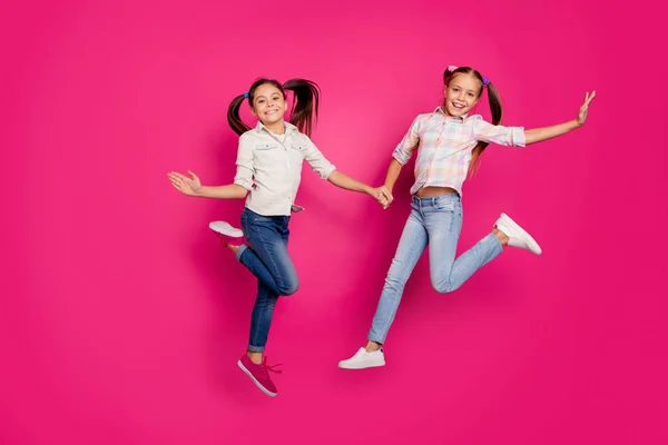 全长身体大小的照片两个小年龄, 她的女孩手手臂跳高胜学校比赛啦啦队员穿休闲牛仔裤牛仔格子格子衬衫孤立粉红色生动生动的背景 — 图库照片