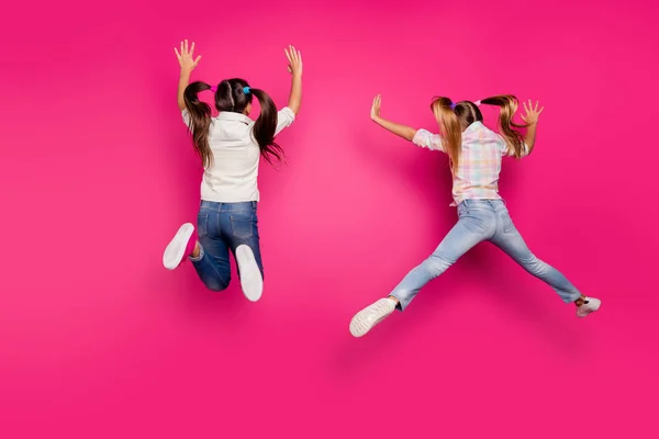 Повна довжина тіла розміром ззаду позаду двох божевільних веселих позитивних попередніх дівчат, які розважаються в повітрі ізольовані на яскравому яскравому блискучому рожевому фоні — стокове фото