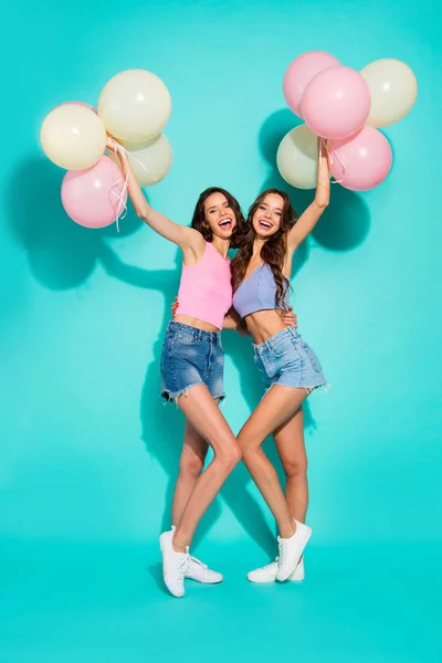 Full length body size photo beautiful cheerful two wavy she her ladies cheerleaders colorful balloons hands arms  wearing shiny jeans denim shorts tank tops isolated teal bright vivid background — Stock Photo, Image