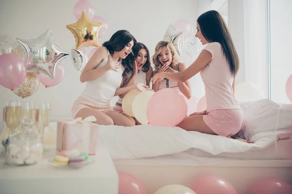 Nueva novia con bonitas y atractivas novias alegres y alegres sentadas en la cama mirando un anillo caro en una habitación interior blanca clara —  Fotos de Stock