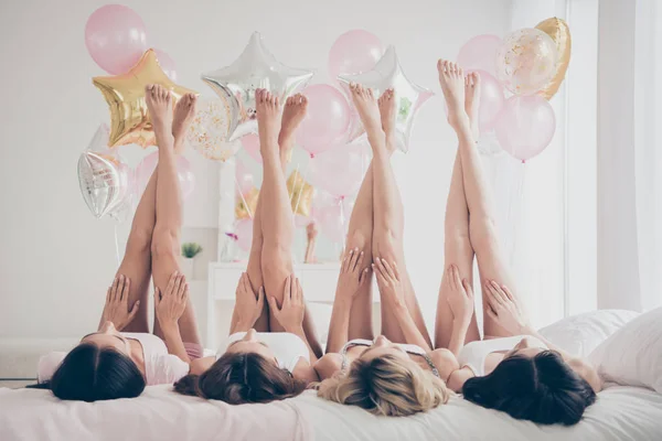 Szép vonzó karcsú fit karcsú alak barátnők szórakozás nevelő sima egészséges lábak a könnyű fehér belső ágyon díszített ház — Stock Fotó