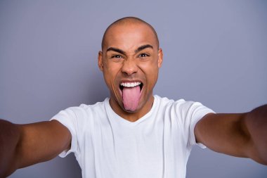 Close up photo healthy masculine dark skin he him his macho bald head funny arms telephone make take selfies tongue out of mouth cheerful wearing white t-shirt outfit clothes isolated grey background clipart