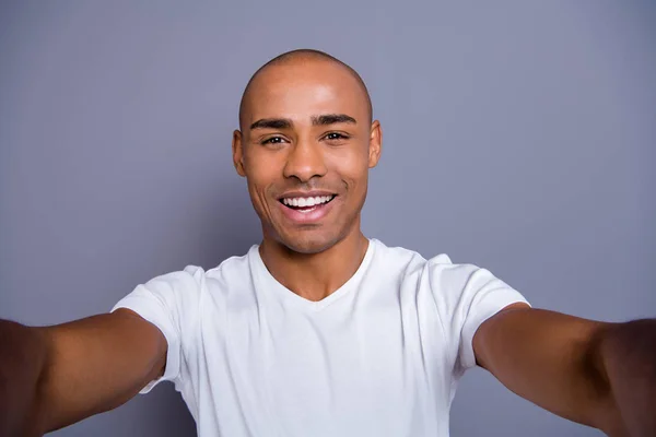 De cerca foto saludable masculino piel oscura él su macho calvo cabeza brazos teléfono hacer tomar selfies alegre usando blanco camiseta traje ropa aislado gris fondo — Foto de Stock