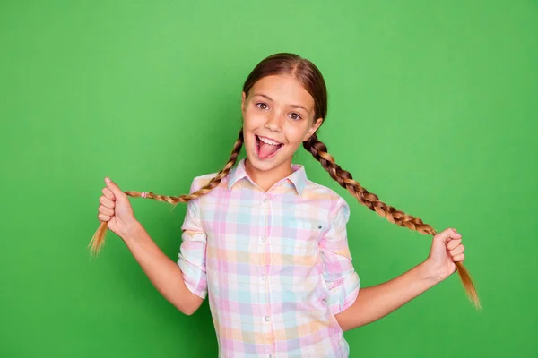 Tutup foto usia kecil dia gadis memegang tangan menunjukkan ekor lidah keluar mulut positif optimis cukup mengenakan kemeja kotak-kotak santai terisolasi hijau cerah latar belakang cerah cerah cerah — Stok Foto