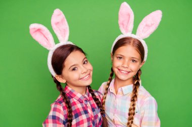 Close-up photo portrait of couple of positive cheerful glad with teeth smile pre teen scholl girls holding painted chocolate eggs looking at camera wear casual plaid shirt isolated vivid background clipart