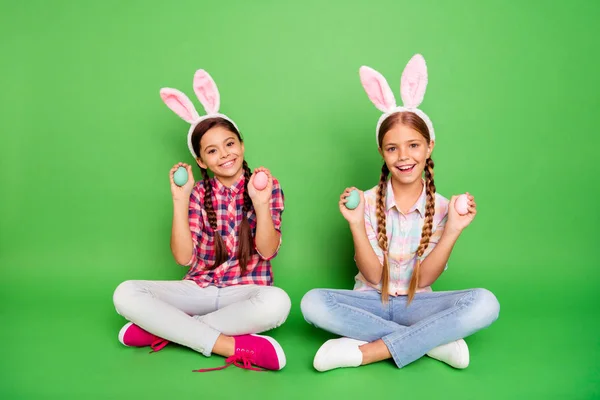 Retrato de dois agradável doce adorável bonito alegre pré-adolescente meninas vestindo camiseta verificada sentado pernas cruzadas preparado pronto para festa isolado sobre brilhante brilho vívido fundo verde — Fotografia de Stock