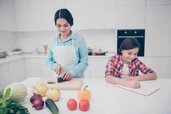 Портрет двух милых симпатичных симпатичных привлекательных веселых веселых мечтательных людей мама делает обед здоровый образ жизни девушка делает домашнюю задачу в светло-белом интерьере кухни в помещении — стоковое фото
