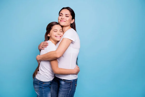 De cerca foto adorable increíble hermosa dos personas de pelo castaño mamá pequeña hija de pie ojos cerrados sosteniendo las manos círculo de brazos con camisetas blancas aisladas sobre fondo azul brillante — Foto de Stock