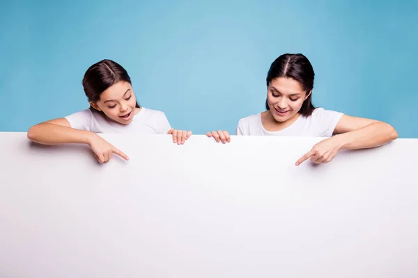 De cerca foto dos personas de cabello castaño mamá pequeña hija mirar hacia abajo en el cartel del letrero brazos dedo mostrar blanco cartel venta descuento usando camisetas aisladas fondo azul brillante — Foto de Stock