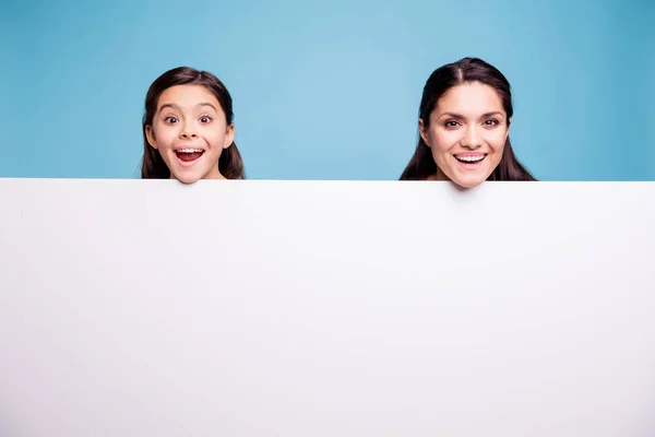 De cerca foto hermosa dos personas de cabello castaño mamá pequeña hija cara mirar letrero cartel con mucho gusto abrir la boca risa risa grito grito gritar usando camisetas aisladas fondo azul brillante — Foto de Stock