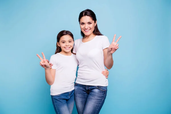 Zbliżenie zdjęcie piękne dwóch osób brązowe włosy Mama córeczkę Wyświetlono v-sign tulenie przyjaciele wyglądają podobnie, noszenie koszulki białe na białym tle jasne niebieskie tło — Zdjęcie stockowe