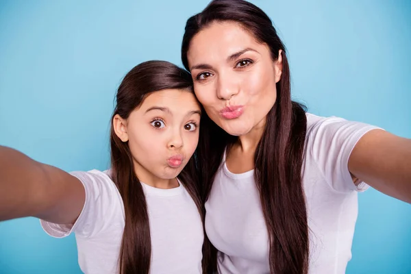 Close up photo cheer two people brown haired mum mom small little daughter make take selfies mouth lips in form shape figure ducky kissing wear white t-shirts isolated bright blue background