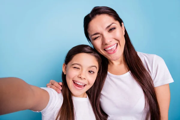 Close up photo cheer beautiful two people brown haired mum mom small little daughter make take selfies mouth laugh laughter flirty wink wear white t-shirts isolated bright blue background
