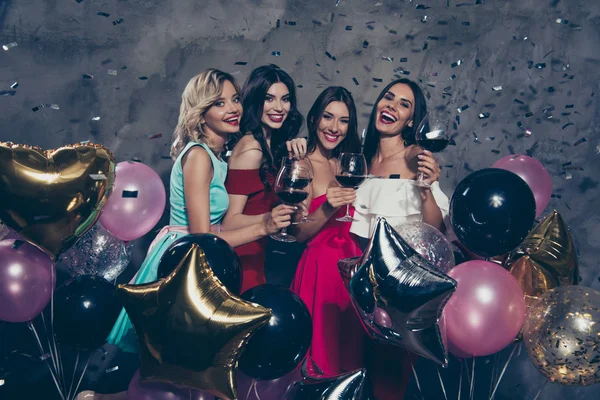 Quatre belles belles belles et fascinantes jolies dames gaies et séduisantes jouissant d'un vin rouge volant des éléments décoratifs s'amusant sur un mur en béton gris — Photo