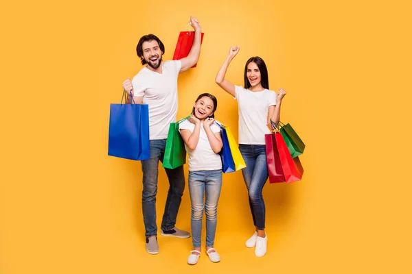 Full length body size view portrait of nice attractive trendy cheerful people holding in hands bags with new clothes having fun rejoice isolated over shine vivid pastel yellow background — Stock Photo, Image