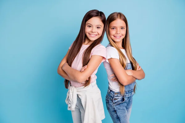 Portrait of nice-looking cute lovely sweet well-groomed attractive cheerful cheery straight-haired girls standing back to back siblings folded arms isolated over blue pastel background — Stock Photo, Image