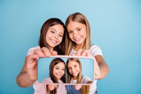 De cerca foto dos poco ella su rubia morena niñas largo bonito pelo teléfono hacer tomar selfies hablar decir hablar millennials usando casual jeans denim camisetas aislado azul brillante fondo —  Fotos de Stock