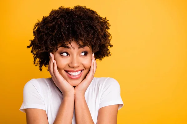 Cerca de la foto hermosa increíble ella sus brazos de señora de piel oscura tocan pómulos mirada se preguntó espacio vacío encantadora sonrisa dentada usando casual camiseta blanca aislado amarillo brillante fondo vivo — Foto de Stock