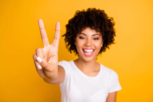 Close up photo beautiful amazed she her her dark skin lady glad arms hands fingers raised show v-sign peaceful hippie concept wearing casual white t-shirt isolated yellow bright background — Foto de Stock
