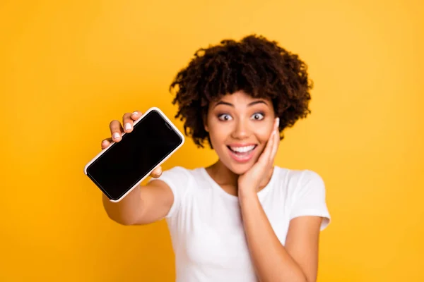 Retrato de ella ella linda linda atractiva alegre alegre alegre sorprendida dama de pelo ondulado sosteniendo en la celda de las manos que muestra dando pantalla negra aislada sobre brillante brillo brillante fondo amarillo — Foto de Stock