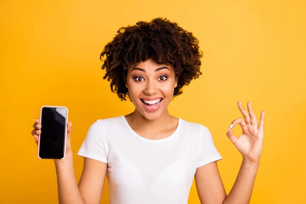 Primer plano retrato de ella ella agradable lindo atractivo encantador alegre alegre extático optimista ondulado de pelo dama sosteniendo en las manos celda mostrando ok-signo aislado sobre brillante brillante brillo amarillo fondo — Foto de Stock