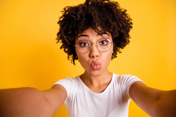 Close up photo beautiful amazing she her dark skin lady lovely send kisses make take selfies cute pretty attractive wear specs casual white t-shirt isolated yellow bright vibrant vivivid background — стоковое фото