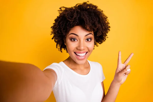 Close up photo beautiful amazing she her dark skin lady arm hand show v-sign make take selfies cute attractive white teeth wear casual white t-shirt isolated yellow bright vibrant vivivid background — стоковое фото