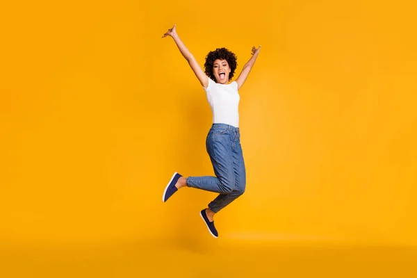 Longitud completa cuerpo tamaño lado perfil foto saltar alto hermosa ella sus manos dama brazos arriba ganar juego juego partido usar casual jeans denim blanco camiseta ropa aislado amarillo brillante fondo vivo — Foto de Stock