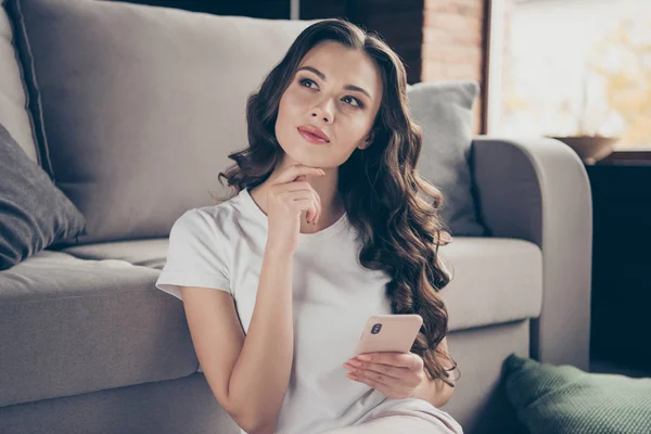 De cerca foto hermosa morena ella su señora teléfono manos brazos imaginación vuelo contemplación usando deportivo luz doméstica color camiseta pantalones ropa traje sentarse piso cómodo diván — Foto de Stock