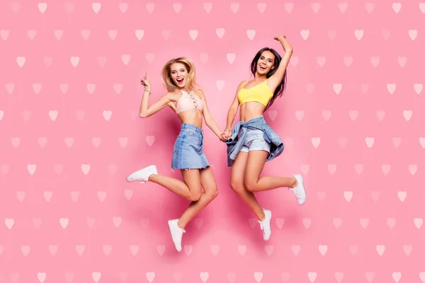 Life is cool Full length body size view of beautiful attractive cheerful careless girls in casual trendy outfit white shoes jumping up holding hands isolated on pastel pink background — стоковое фото