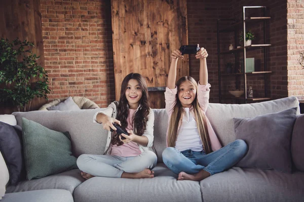 Porträt von zwei schönen hübschen süßen entzückenden attraktiven charmanten lustigen fröhlichen positiven Mädchen sitzen auf Diwan spielen Videospiel Schlacht gekreuzten Beinen im Haus Loft Industrial Interior-Stil — Stockfoto