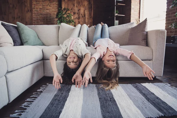 Zwei schöne schöne attraktive charmante verschiedene fröhliche fröhliche freundliche Mädchen, die auf dem Kopf auf dem Sofa liegen und einen unterhaltsamen Tag im industriellen Interieur-Stil des Hauses haben — Stockfoto