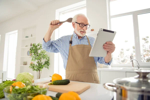 Close up photo grey haired he his him grandpa hands arms e-reader sorry guilty face wrong ingredient afraid scared of consequences wear specs casual checkered plaid shirt jeans denim outfit kitchen