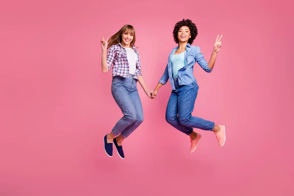 Longitud completa vista del tamaño del cuerpo de dos personas de aspecto agradable encantadora encantadora encantadora alegre divertido niñas cogidas de la mano mostrando v-signo aislado sobre fondo pastel rosa —  Fotos de Stock