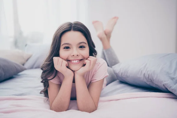 Close up photo cute sweet beautiful she her little girl crossed legs lying down pillow hands arms hold head homey sunday wear home t-shirt pants comfortable apartments flat bright light colored room — Stock Photo, Image