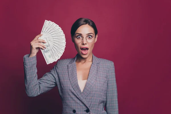 Retrato dela ela agradável atraente encantador alegre espantado surpreendido atordoado engraçado senhora em cinza verificado jaqueta mostrando 100 nós dinheiro orçamento recomendo isolado sobre maroon Borgonha marsala fundo — Fotografia de Stock