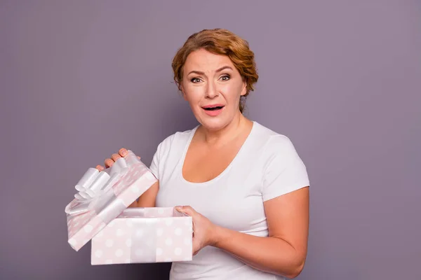 Portrait of her she nice attractive charming sad childish mom wavy-haired lady in casual white t-shirt holding in hands unpacking desirable box isolated on gray violet purple pastel background