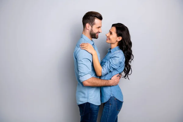 Zuneigung. Profil Seitenansicht Foto von hübschen Gelegenheitspartnern, die zufrieden in die Augen schauen, erfreut die Gesellschaft in blauen Jeanshemden gekleidet, die isoliert über schroffem Hintergrund stehen — Stockfoto