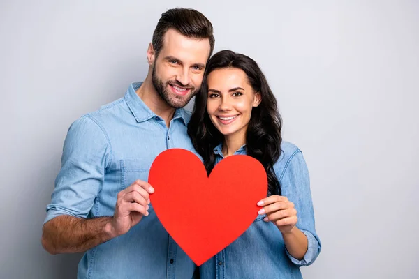 巨大的形状纸卡心脏。可爱粘合英俊的夫妇的肖像显示情人节礼物呈现的感情穿着休闲牛仔衬衫隔离在灰灰色的背景 — 图库照片