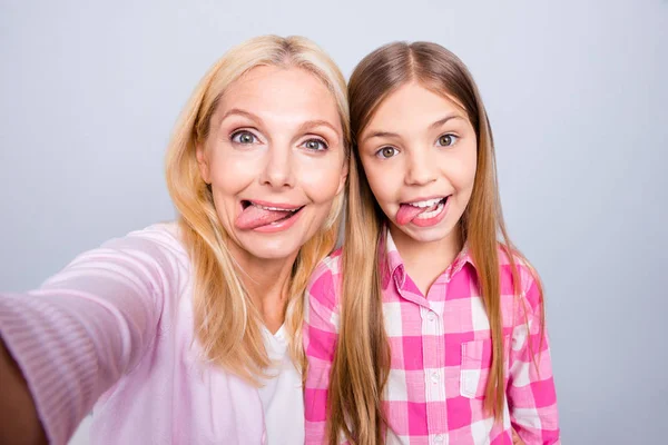 Närbild foto cheer två personer blond haired hon hennes mormor lilla dotter göra ta selfies tungan ut munnen helgen slitage rosa Pläd rutig skjorta tröja pullover isolerade ljus grå bakgrund — Stockfoto