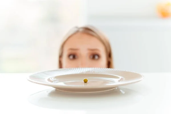 Foto vista cortada de ervilhas pequenas no prato redondo grande na cozinha mesa limpa branca bonito muito triste senhora decepcionada olhando pobre — Fotografia de Stock