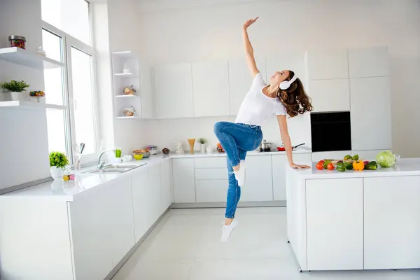 Lunghezza completa dimensione del corpo vista di lei lei bello-looking attraente forte allegro allegro ragazza dai capelli ondulati avendo mano divertente sul tavolo alzando in luce moderna camera in stile interno bianco — Foto Stock