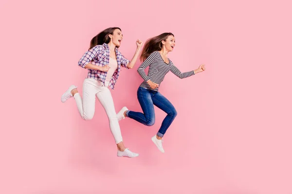 Longitud completa tamaño corporal foto de adolescentes excitados activos divertido funky engañar descuidado tener paseo moviéndose rápido usando jeans blusas a cuadros aislados sobre fondo rosa —  Fotos de Stock