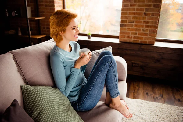 Close up side profile photo beautiful she her lady hands hot beverage stay home lazy peaceful mood listen toothy wear blue casual pullover jeans denim sit comfy divan house living room indoors — стоковое фото